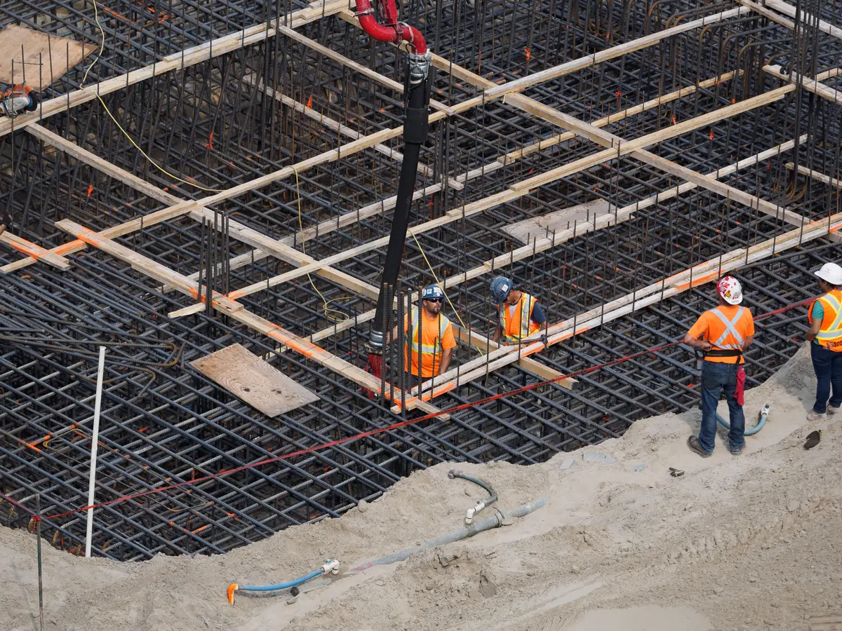 A tied rebar grid over compacted base with the concrete pump line in position