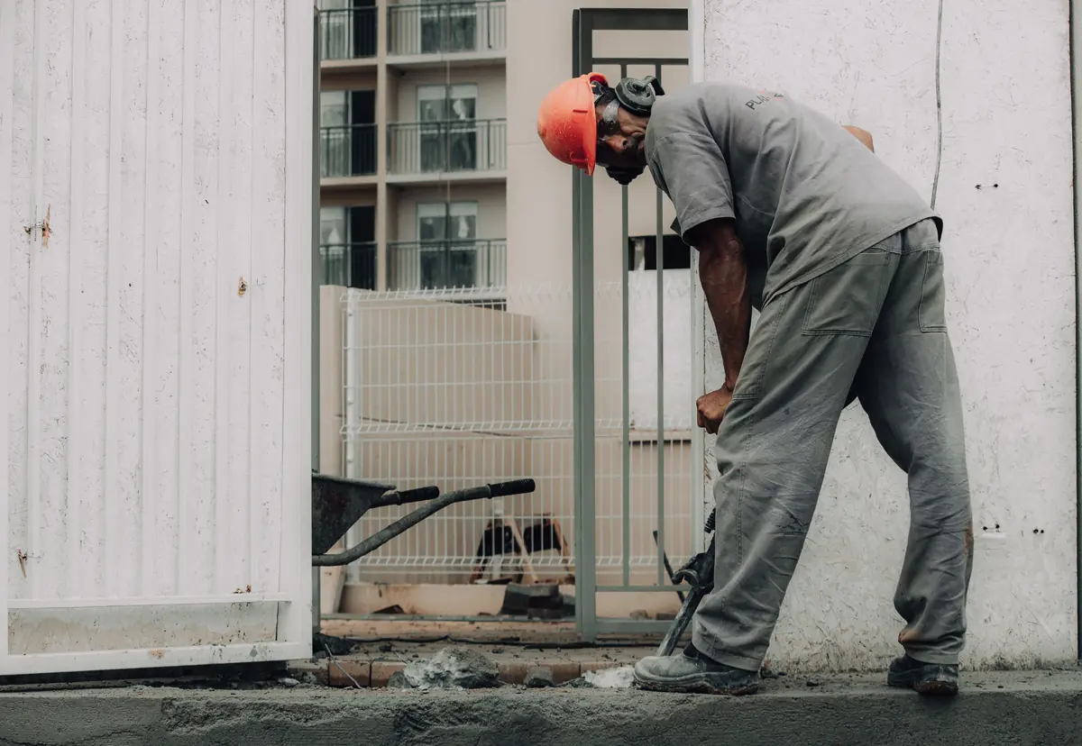 A worker breaking out a concrete slab with a handheld breaker