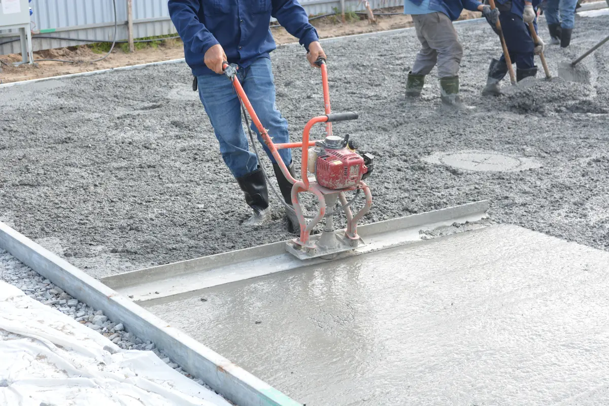 A crew running a power screed across a freshly placed concrete slab