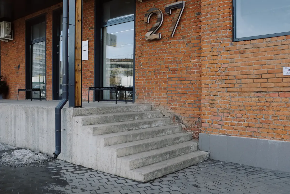 A short flight of poured concrete entrance steps with a landing at the door